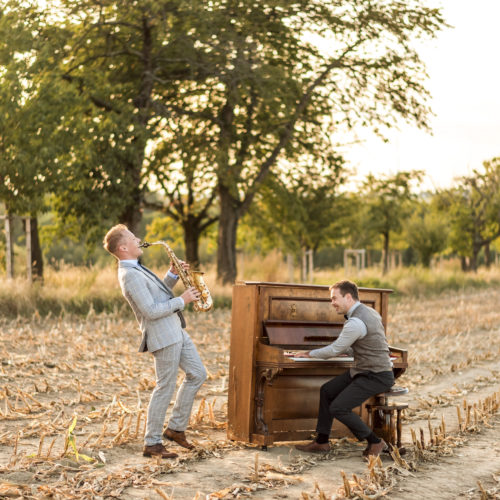 Das sächsische Duo kalobao spielt live mit Saxophon und Piano auf einem Feld